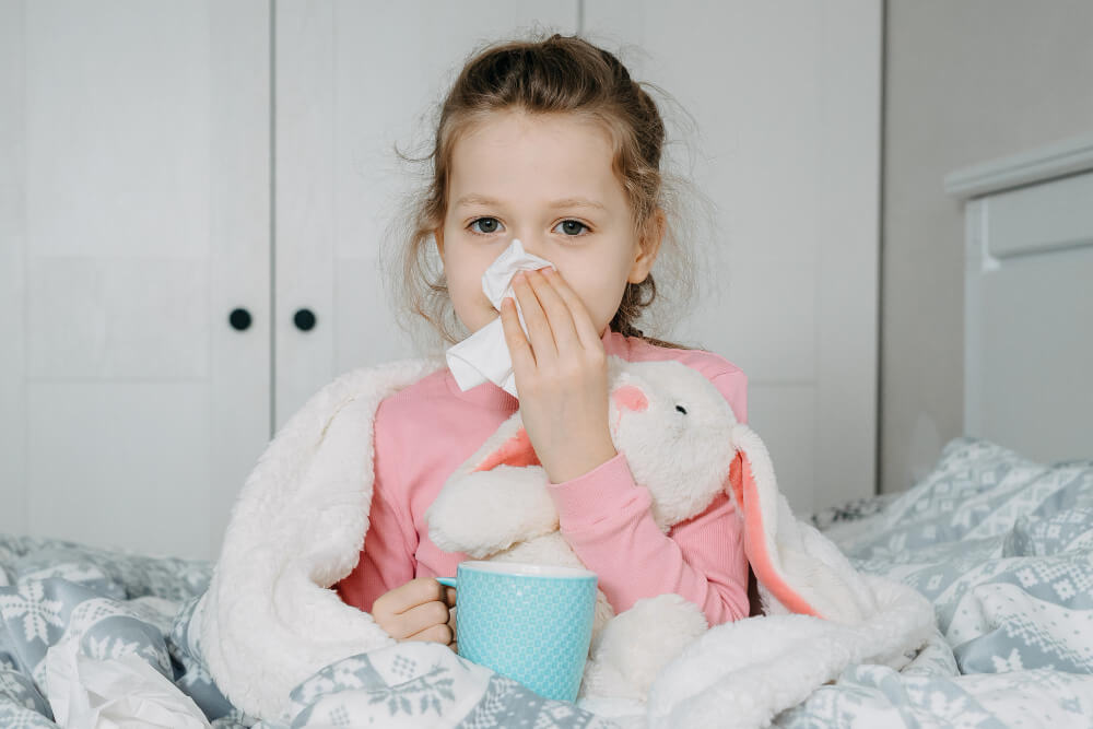 Niña con resfriado en una cama con un pañuelo